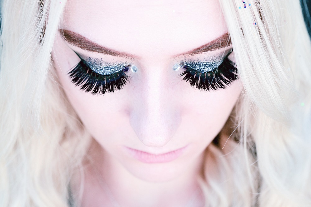 close up of women wearing false eyelashes and glitter eye shadow